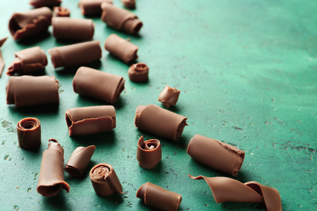 Delicious chocolate curls on color background