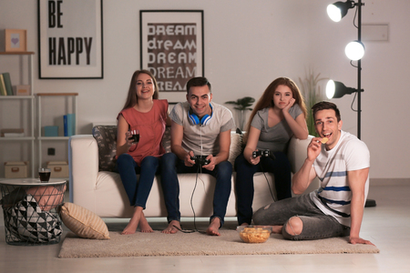 Young people playing video games at home in eveningの写真素材