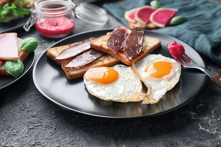 Plate with toasted bread and eggs on textured tableの写真素材