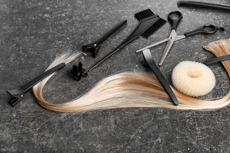 Professional hairdresser's set with strand of blonde hair on grey backgroundの写真素材