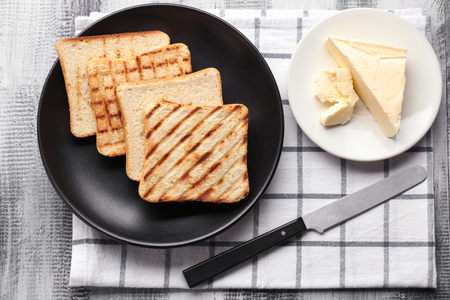 Plates with toasted bread and butter on tableの写真素材