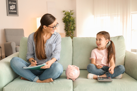 Mother and daughter counting money  indoors. Money savings conceptの写真素材
