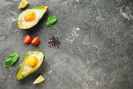 Baked avocado with eggs and vegetables on grey textured backgroundの写真素材