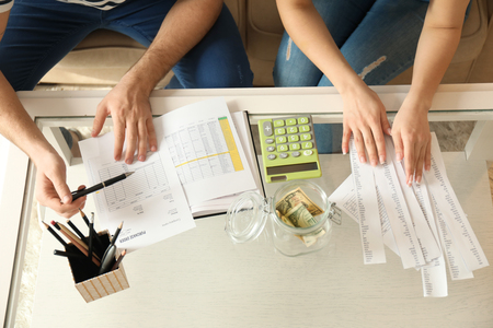 Couple with pay bills, calculator and money counting expenses indoors. Money savings conceptの写真素材