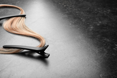 Clips with strand of blonde hair on grey backgroundの写真素材