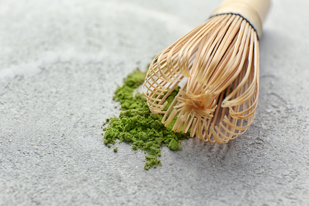 Powdered matcha green tea with whisk on grey backgroundの写真素材