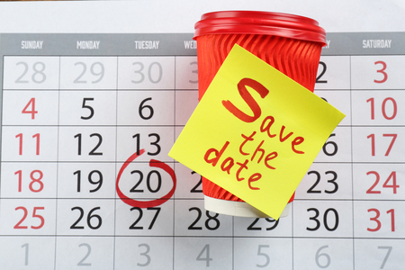 Cup and sheet of paper with text "Save the Date" on calendarの写真素材