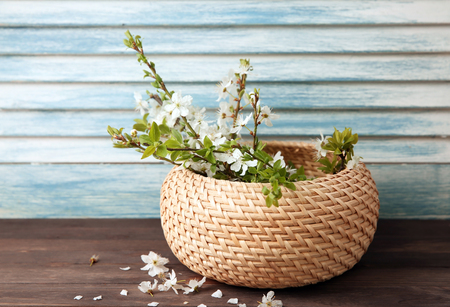 Wicker box with blossoming branches on wooden tableの写真素材