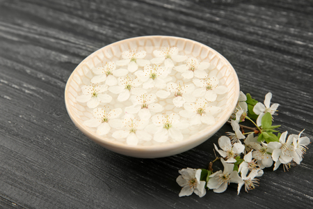 Plate with water and blooming flowers on dark wooden backgroundの写真素材