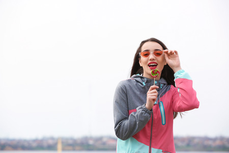 Attractive young woman with lollipop outdoorsの写真素材