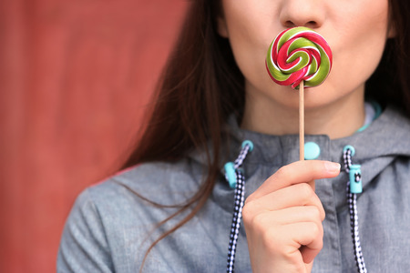 Attractive young woman with lollipop on blurred background, closeupの写真素材