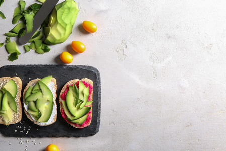 Delicious toasts with avocado on slate plateの写真素材
