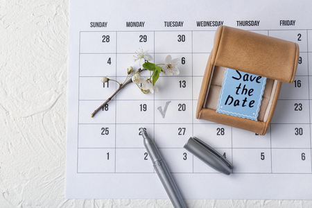 Box with "Save the Date" card, marker and blooming branch on calendarの写真素材