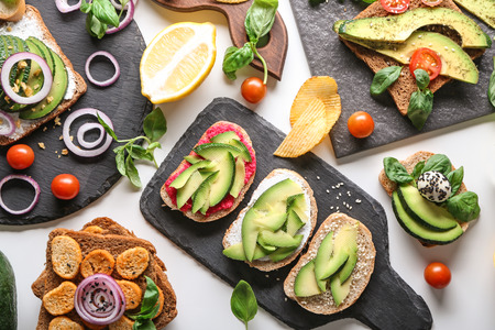 Delicious toasts with avocado on slate plates