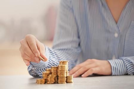 Woman stacking coins on tableの写真素材