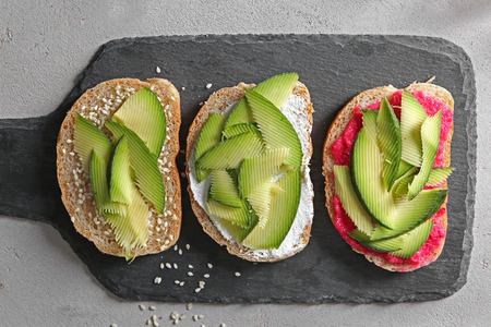 Delicious toasts with avocado on slate plate