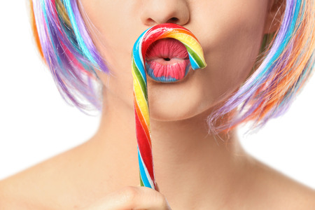 Beautiful young woman with creative makeup and candy cane on white background, closeupの写真素材
