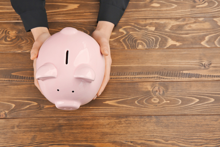 Woman with piggy bank on wooden backgroundの写真素材