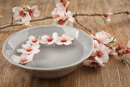 Plate with water and blooming flowers on wooden backgroundの写真素材