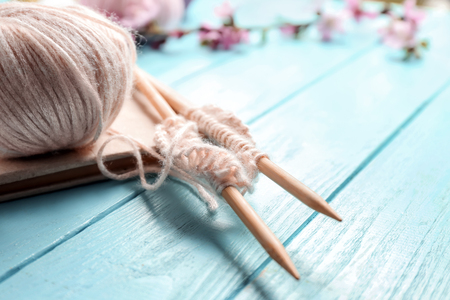 Ball of knitting yarn with needles and book on wooden tableの写真素材