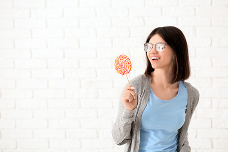 Beautiful young woman with lollipop on light backgroundの写真素材