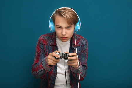 Teenager with gamepad on color backgroundの写真素材