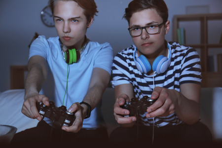 Teenagers playing video games at home late in the evening