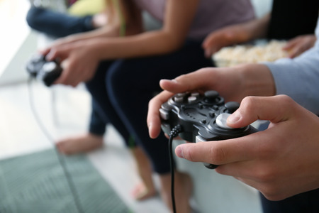 Teenagers playing video games at home, closeup