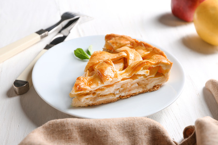 Plate with piece of tasty apple pie on wooden tableの写真素材