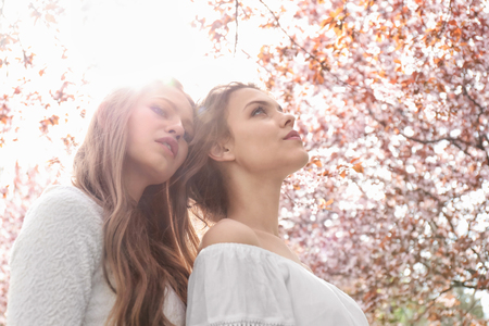 Beautiful young women in park with blooming trees on spring dayの写真素材