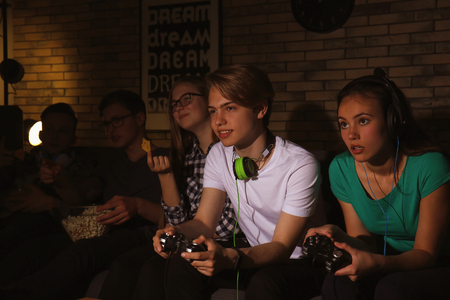 Teenagers playing video games at home late in the eveningの写真素材