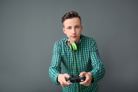 Teenager with gamepad on grey backgroundの写真素材