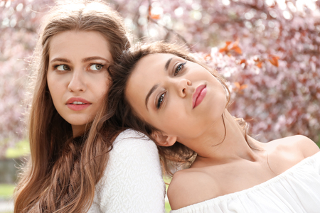 Beautiful young women in park with blooming trees on spring dayの写真素材