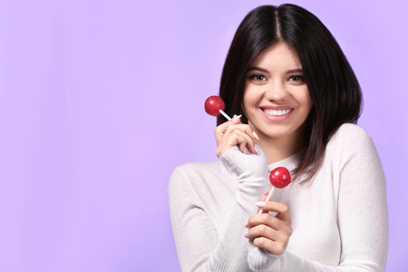 Beautiful young woman with lollipops on color backgroundの写真素材
