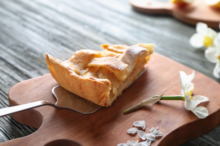 Wooden board with piece of tasty apple pie on tableの写真素材