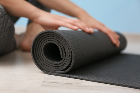 Young woman with yoga mat indoors, closeupの写真素材
