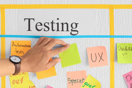 Man attaching sticky note to scrum task board in officeの写真素材