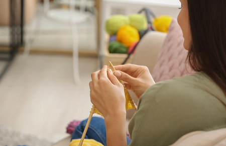 Young woman knitting warm sweater indoors, closeupの写真素材
