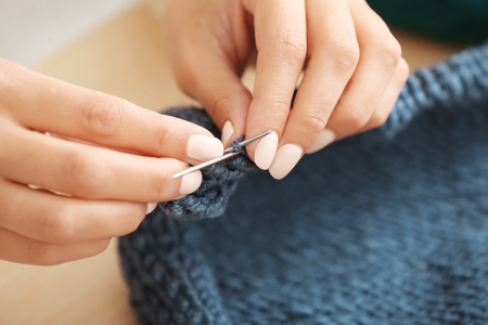 Young woman knitting warm sweater indoors, closeupの写真素材