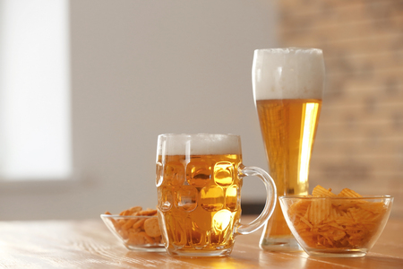 Glasses with beer and snacks on table in barの写真素材