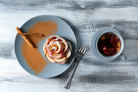 Plate with rose shaped apple pastry and cinnamon on tableの写真素材