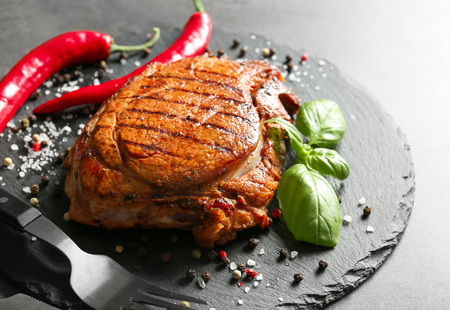 Slate plate with tasty grilled steak and spices on tableの写真素材