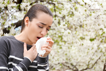 Young woman with nose wiper near blooming tree. Allergy conceptの写真素材