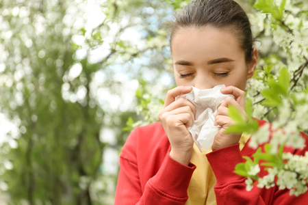 Young woman with nose wiper near blooming tree. Allergy conceptの写真素材