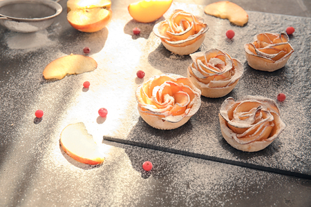 Slate board with tasty apple roses from puff pastry on tableの写真素材