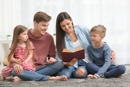 Happy family reading book together at homeの写真素材