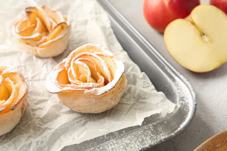 Baking tray with tasty apple roses from puff pastry on tableの写真素材
