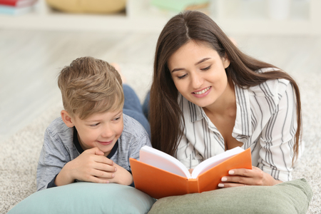 Mother and her son reading book together at homeの写真素材