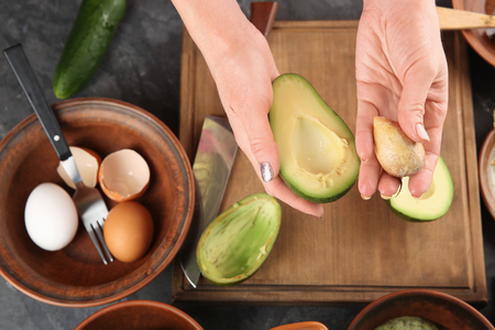 Woman making nourishing mask with avocadoの写真素材