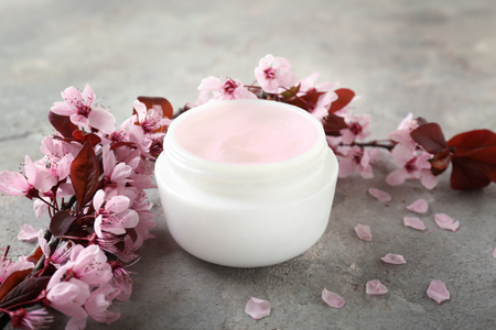 Jar of cream with blossoming branch on tableの写真素材